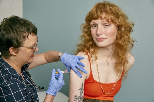 A woman with long red hair receiving a vaccination shot