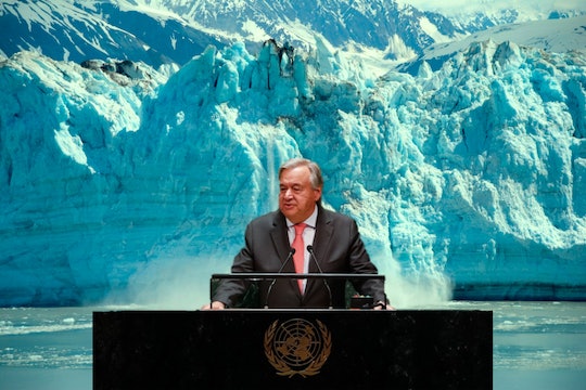 Antonio Guterres stands at a desk in front of a calving glacier