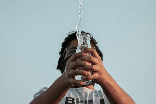 a man spilling water out of a glass jar, photographed from below