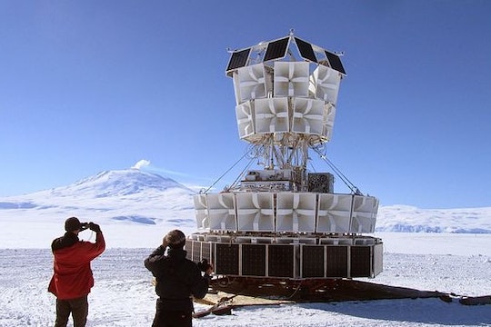 two people looking at a giant white ballon structure in antarctica