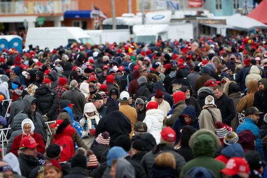 A crowd of people, many of which have red baseball caps.