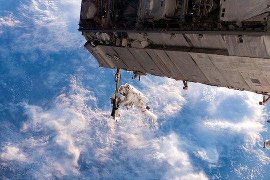 astronaut working on the international space station against a backdrop of clouds