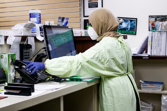 a woman wearing protective gear in a hospital working at a computer
